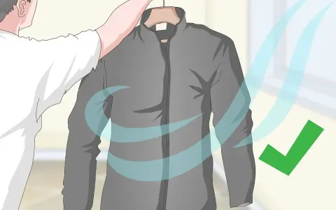 Eine graue Fleecejacke wird zum Trocknen aufgehängt. Blaue Wellen symbolisieren Luftzirkulation, ein grüner Haken zeigt Erfolg an. So wird die Fleecejacke gewaschen und getrocknet.