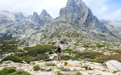 Wanderer in Korsika im August, genießt die kühlen Bergtage. Die majestätischen Gipfel und die raue Landschaft laden zum Erkunden ein.