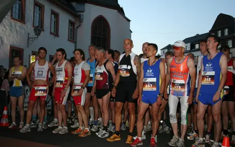 Läufer warten am Start des Sommernachtslauf Limburg. Sie tragen Laufbekleidung und Startnummern.