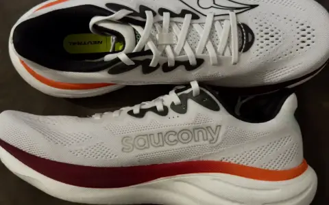 Zwei weiße Laufschuhe, die Saucony Ride 19, mit roten und orangen Akzenten. Perfekt für neutrale Läufer.