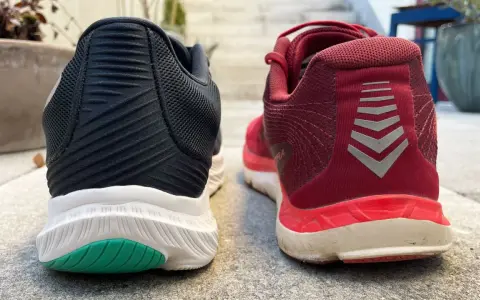 Zwei Laufschuhe, ein schwarzer und ein roter, stehen nebeneinander. Der rote Schuh trägt das Logo "altra rivera".