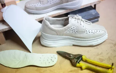 Schuhe mit Abrollsohle im Test: Ein Muster, eine Sohle und eine Schere liegen bereit.