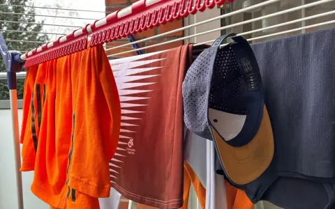 Wäscheleine mit Kleidung, darunter ein orangefarbenes Shirt, ein braunes Shirt und eine Kappe, die zum cap reinigen aufgehängt wurde.