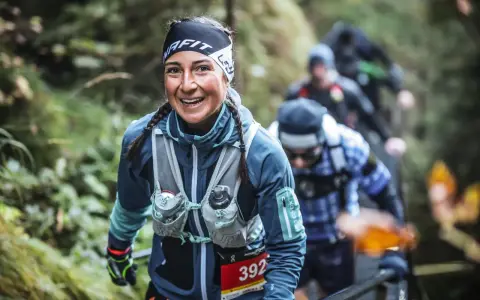 Lächelnde Läuferin beim Mountainman Nesselwang Trailrun. Sie trägt Sportkleidung und hat Zöpfe.
