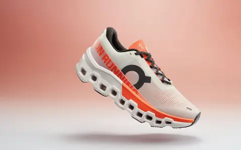 Ein weißer Laufschuh mit orangefarbenen Akzenten, der Cloudmonster 2 Herren, schwebt vor einem sanften Farbverlauf.