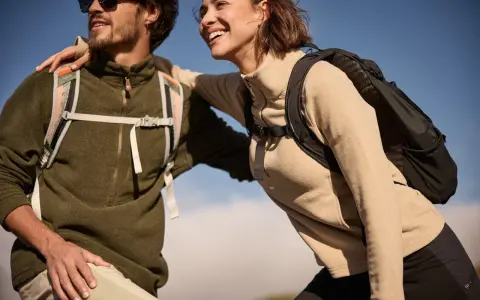 Glückliches Paar in warmen Fleece-Pullovern und Rucksäcken genießt die Natur. Fleece ist weich und isolierend.