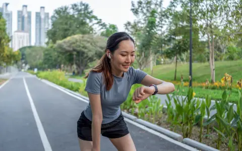 Läuferin prüft ihren Puls beim Joggen. Ihr Herz schlägt bei 180 Schlägen pro Minute. Sie ist eine Frau, die fit ist.