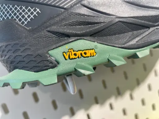 Detailaufnahme einer grünen Vibram Sohle mit gelbem Logo. Mögliche Nachteile: Abnutzung des Profils bei starker Beanspruchung.