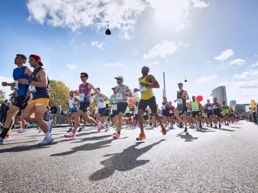 Läufer in einem Marathon, die ihr Lungenvolumen trainieren. Die Sonne scheint, der Himmel ist blau mit Wolken.