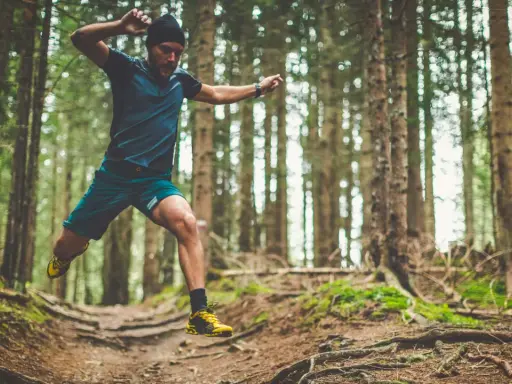 Mann im Sprung beim trailrunning training im Wald.