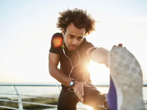 Mann dehnt sich am Meer, wichtig für die Regeneration nach Halbmarathon.