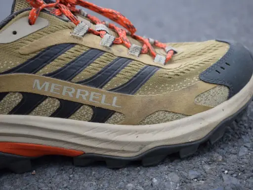 Detailaufnahme eines Merrell Wanderschuhs im Test. Der Schuh ist in Beige- und Brauntönen gehalten, mit orangefarbenen Schnürsenkeln und schwarzen Akzenten.