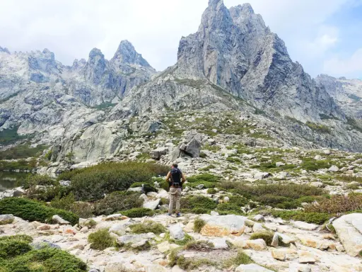 Wanderer in Korsika im August, genießt die kühlen Bergtage. Die majestätischen Gipfel und die raue Landschaft laden zum Erkunden ein.