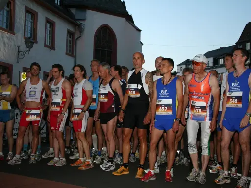 Läufer warten am Start des Sommernachtslauf Limburg. Sie tragen Laufbekleidung und Startnummern.