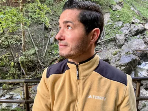 Mann in gelber Fleecejacke mit schwarzem Kragen und Schulterpartien, die zeigt, welche Fleecejacke wirklich warm ist.