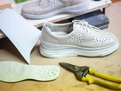 Schuhe mit Abrollsohle im Test: Ein Muster, eine Sohle und eine Schere liegen bereit.