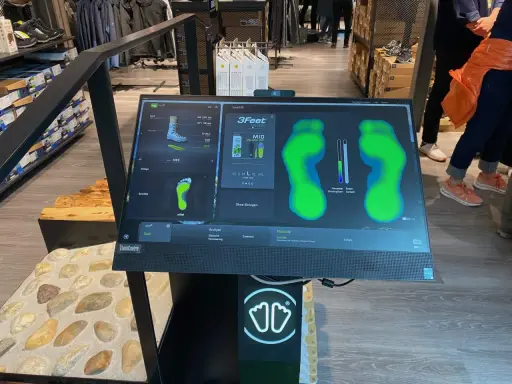Bildschirm zeigt eine Laufschuh Analyse mit Fußabdrücken und Druckpunkten. Die Software "Smartfit" hilft bei der Auswahl des passenden Schuhs.