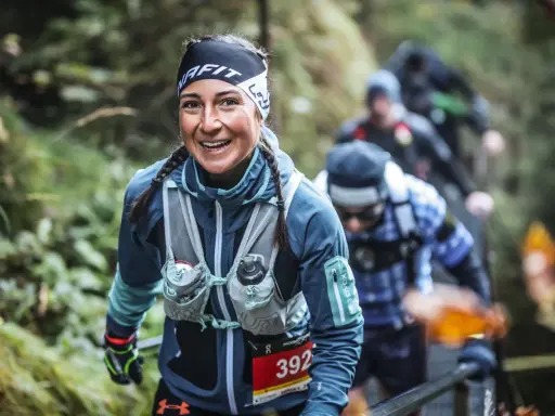 Lächelnde Läuferin beim Mountainman Nesselwang Trailrun. Sie trägt Sportkleidung und hat Zöpfe.