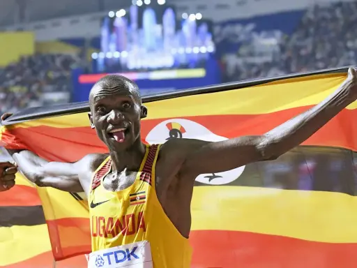 Läufer mit ugandischer Flagge, jubelt nach einem 5km-Weltrekord.
