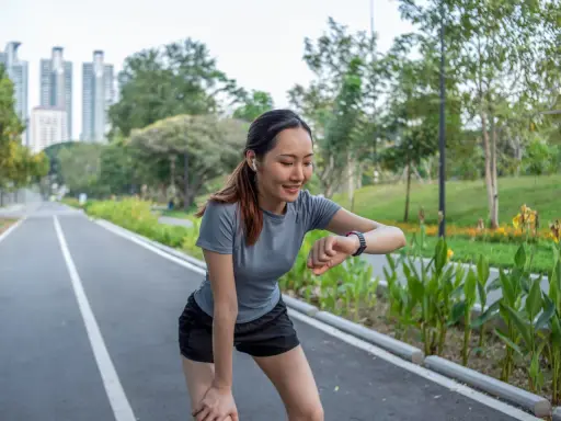 Läuferin prüft ihren Puls beim Joggen. Ihr Herz schlägt bei 180 Schlägen pro Minute. Sie ist eine Frau, die fit ist.