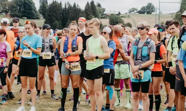 Läufer stehen bereit für den Lauf "3 Kings 3 Hills". Die Teilnehmenden tragen Startnummern und Laufbekleidung.