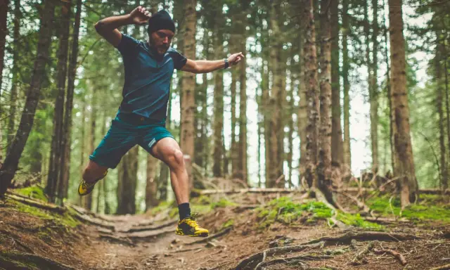 Mann im Sprung beim trailrunning training im Wald.
