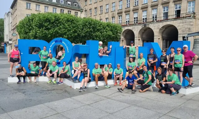 Gruppe feiert Erfolg beim urban run Bochum vor riesiger blauer Schrift.