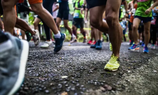 Läufer auf einer Strecke, bereit für die Halbmarathon Distanz. Beine in Bewegung, die Ziellinie im Blick.