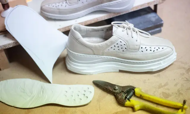 Schuhe mit Abrollsohle im Test: Ein Muster, eine Sohle und eine Schere liegen bereit.