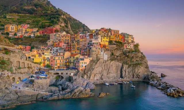 Bunte Häuser klammern sich an einen Felsen über dem Meer. Ein perfekter Ort für **La Spezia Wandern** und unvergessliche Ausblicke.