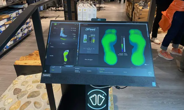 Bildschirm zeigt eine Laufschuh Analyse mit Fußabdrücken und Druckpunkten. Die Software "Smartfit" hilft bei der Auswahl des passenden Schuhs.