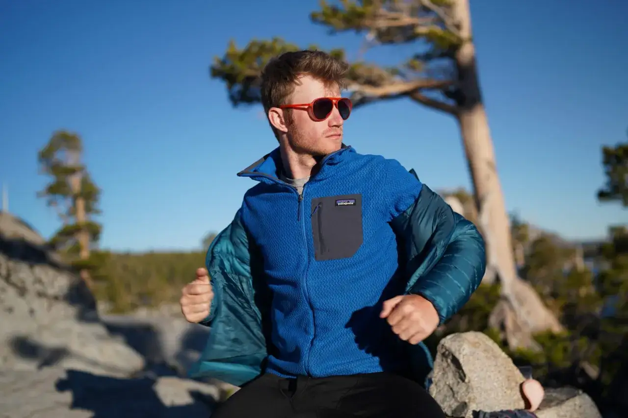 Mann zieht blaue Fleecejacke mit Patagonia-Logo an. Das weiche Material ist ideal f&uuml;r Outdoor-Abenteuer.