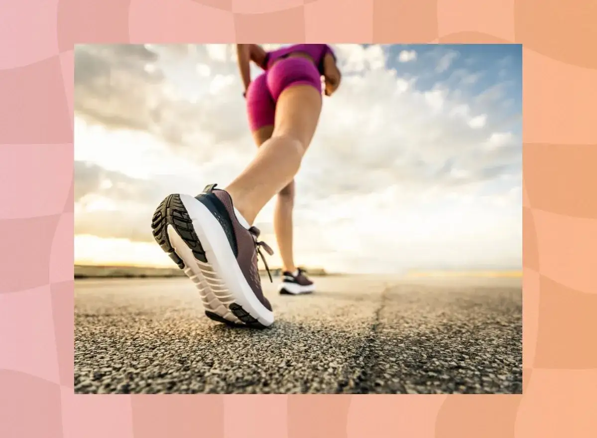 Beine in pinken Shorts und Laufschuhen beim Power Walking auf einer Stra&szlig;e bei Sonnenuntergang.