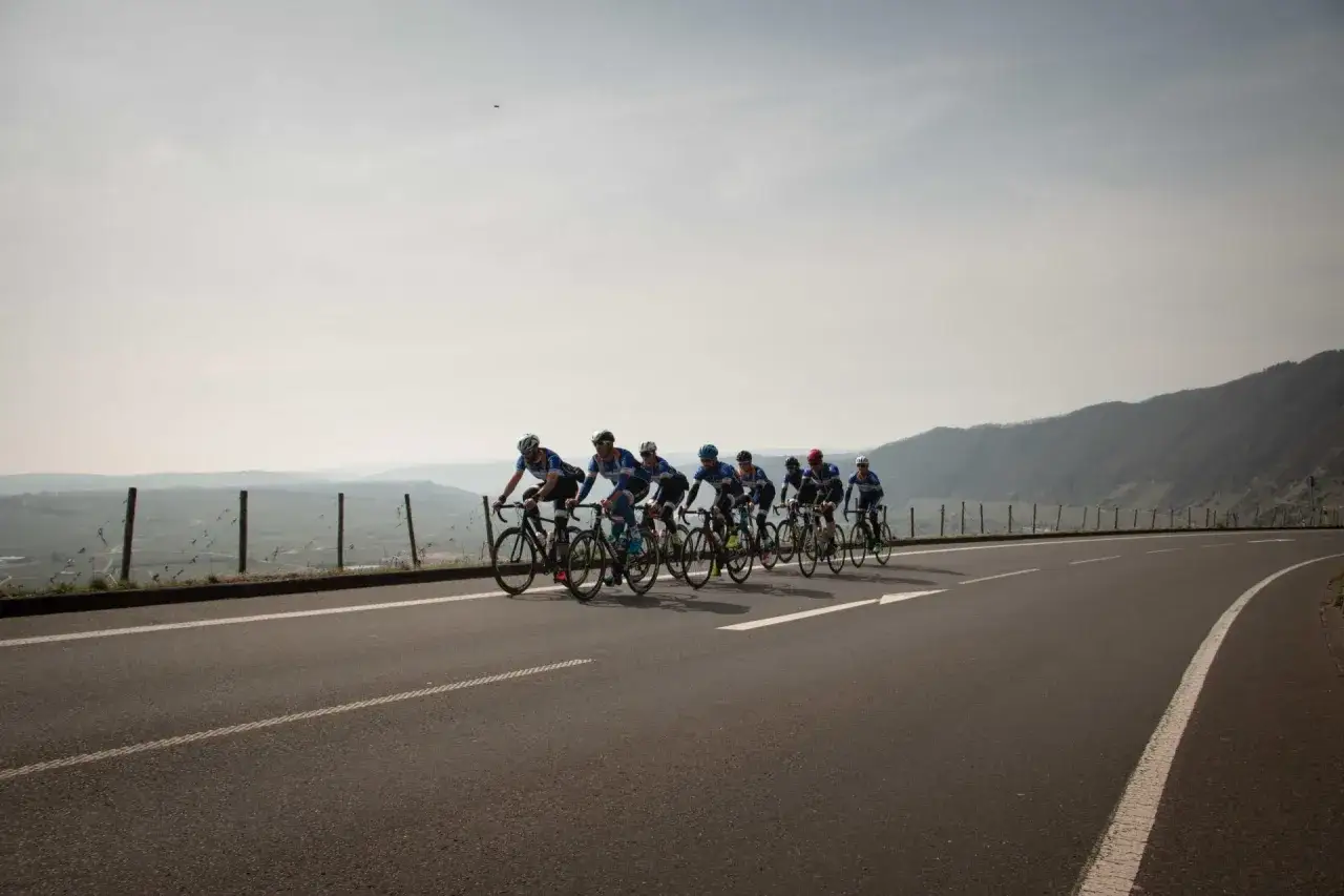 Radfahrer in blauen Trikots kämpfen sich bergauf, ein Bild der Ausdauer, das an den Ironman Luxembourg erinnert.