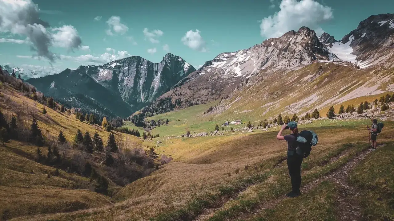 Zwei Wanderer genießen die Aussicht auf majestätische Berge, ein perfektes Bild für fernwanderwege frankreich.