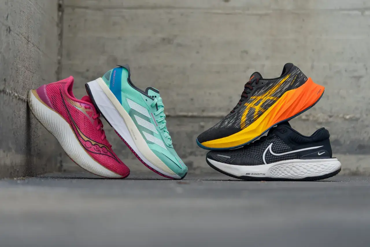 Vier Laufschuhe in leuchtenden Farben, darunter ein pinker, ein mintgrüner, ein gelb-orangefarbener und ein schwarzer, stehen vor einer Betonwand. Die altra rivera Kollektion inspiriert zu neuen Rekorden.