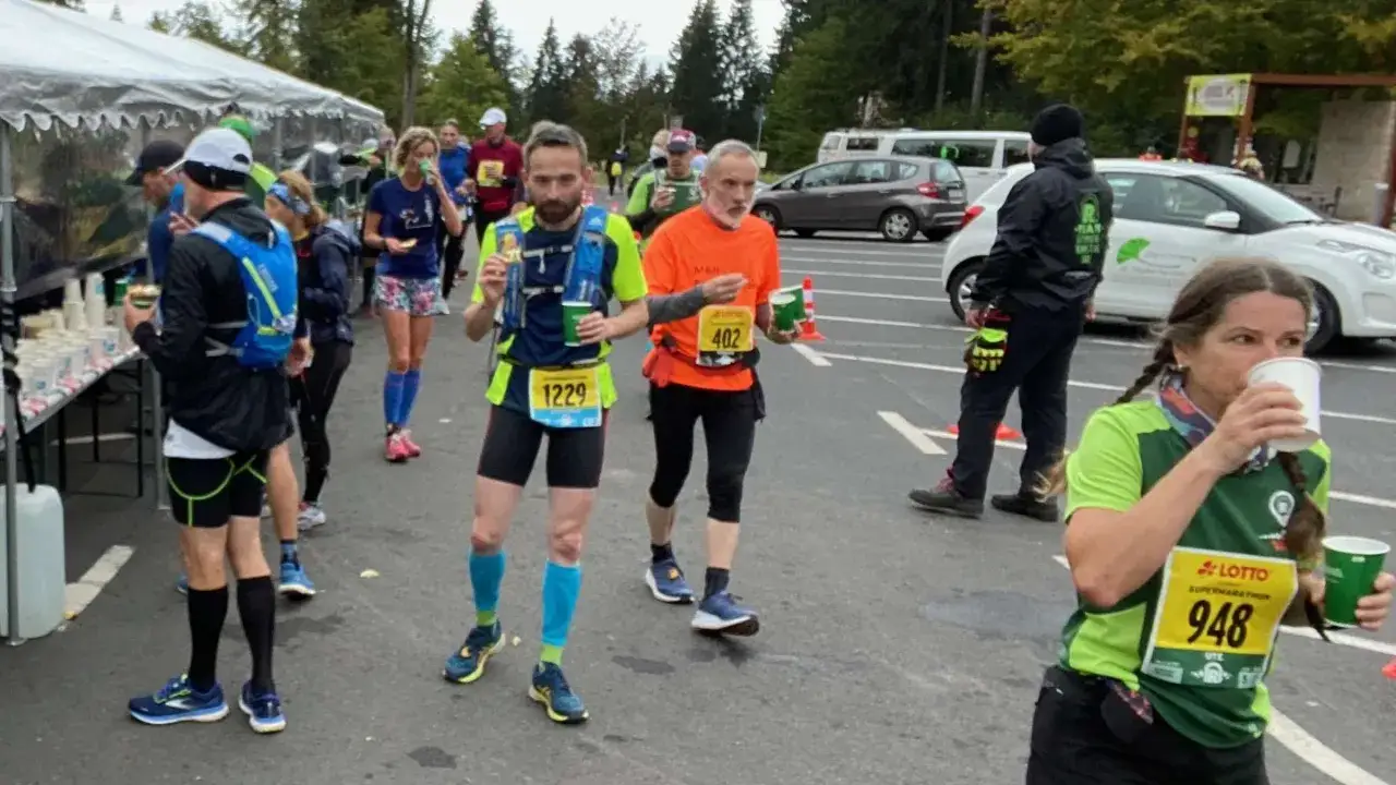 Läufer mit Startnummern erfrischen sich bei einer ultramarathon distanz.