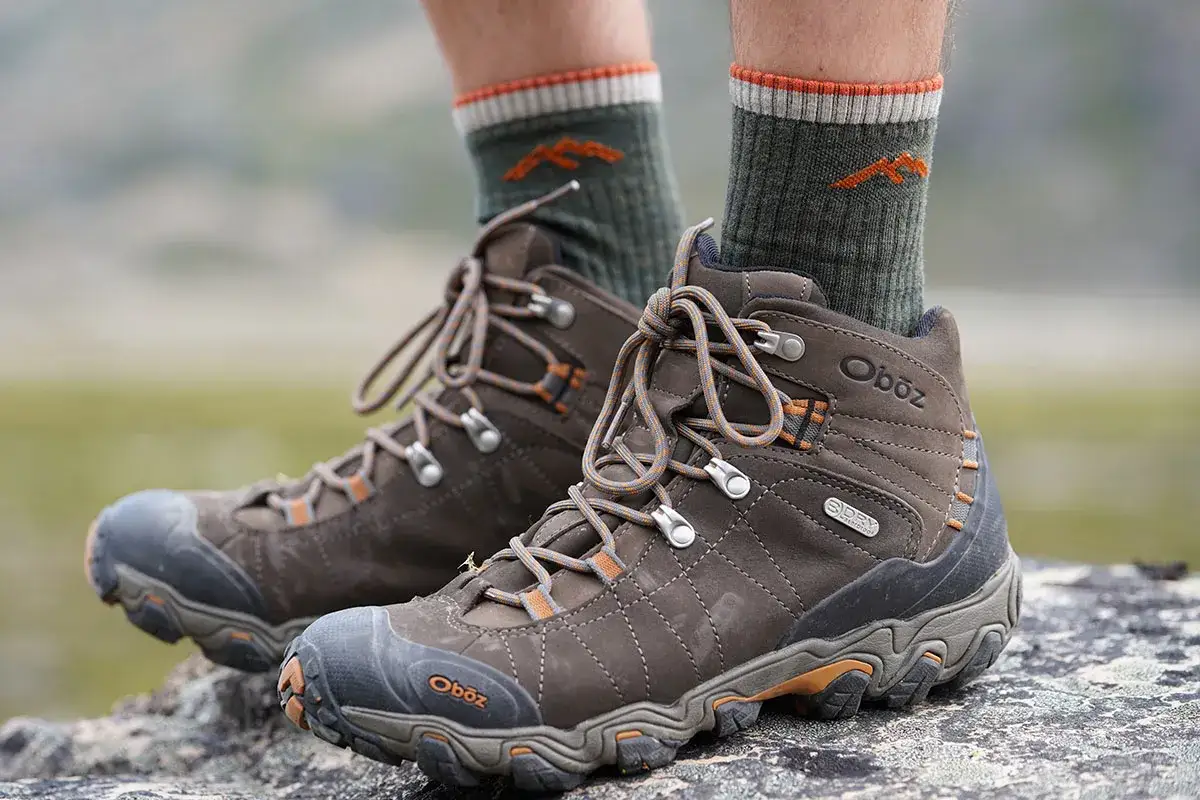 Bereit f&uuml;r jedes Abenteuer: Braune Wanderschuhe mit gr&uuml;nen Socken, die mit einem orangefarbenen Bergmotiv verziert sind.