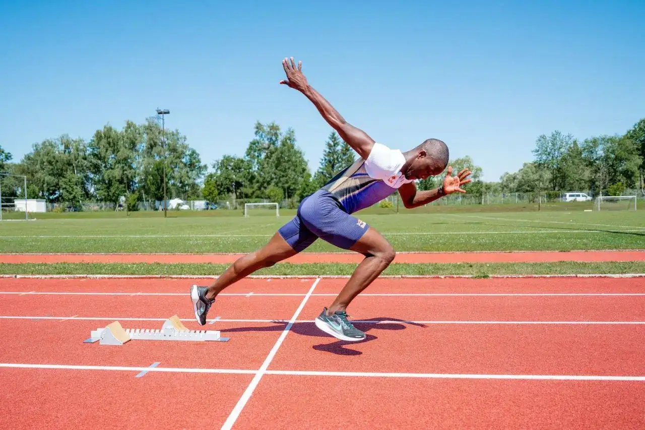 Ein Sprinter in voller Aktion, bereit f&uuml;r explosive Starts. Sein Training, das plyometrisches Training einschlie&szlig;t, zeigt sich in seiner kraftvollen Haltung.