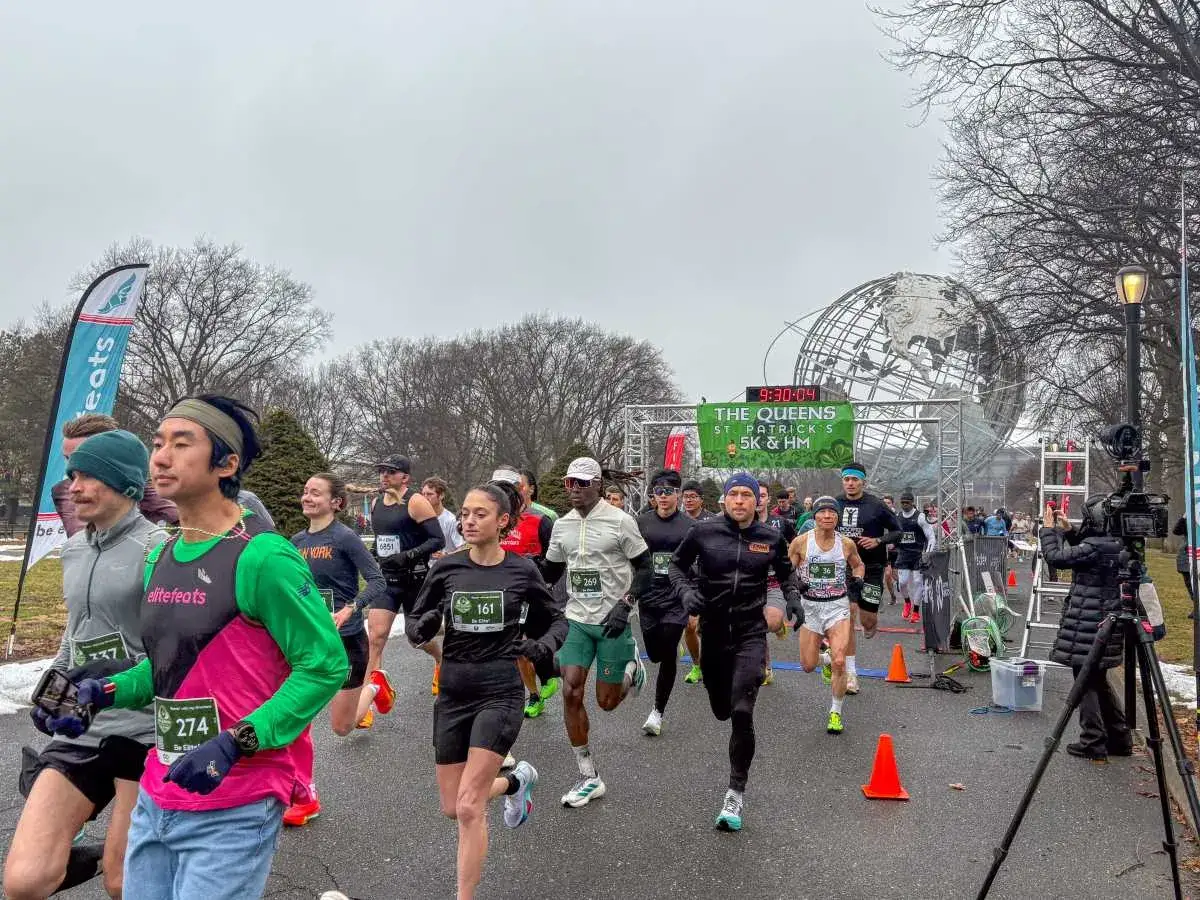 Läufer starten den 5 km lauf in Queens, New York, mit dem Unisphere im Hintergrund.