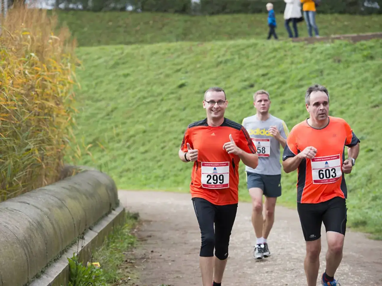 Läufer beim Leipzig Run im Herbst. Drei Männer in Sportkleidung auf einem Feldweg, zwei davon mit Startnummern.