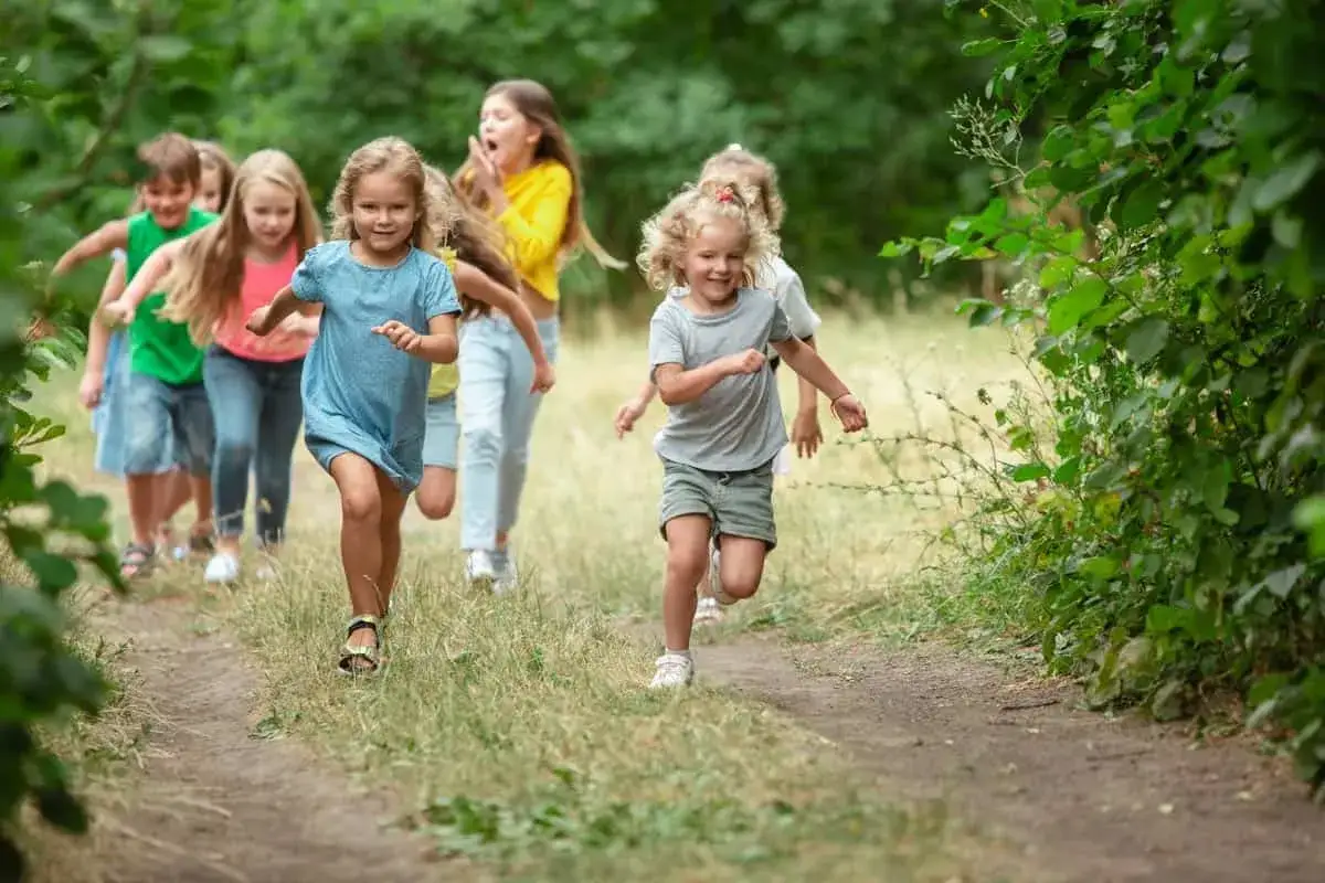 Fr&ouml;hliches lauftraining kinder auf einem Waldweg. Kinder rennen lachend durch die Natur, voller Energie und Freude.