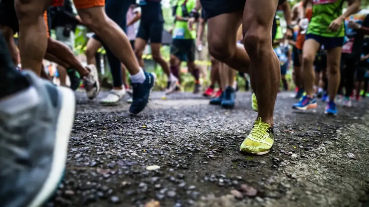 L&auml;ufer im Halbmarathon, die ihre Zeiten nach Alter verbessern. Viele Beine in Bewegung auf einem Schotterweg.