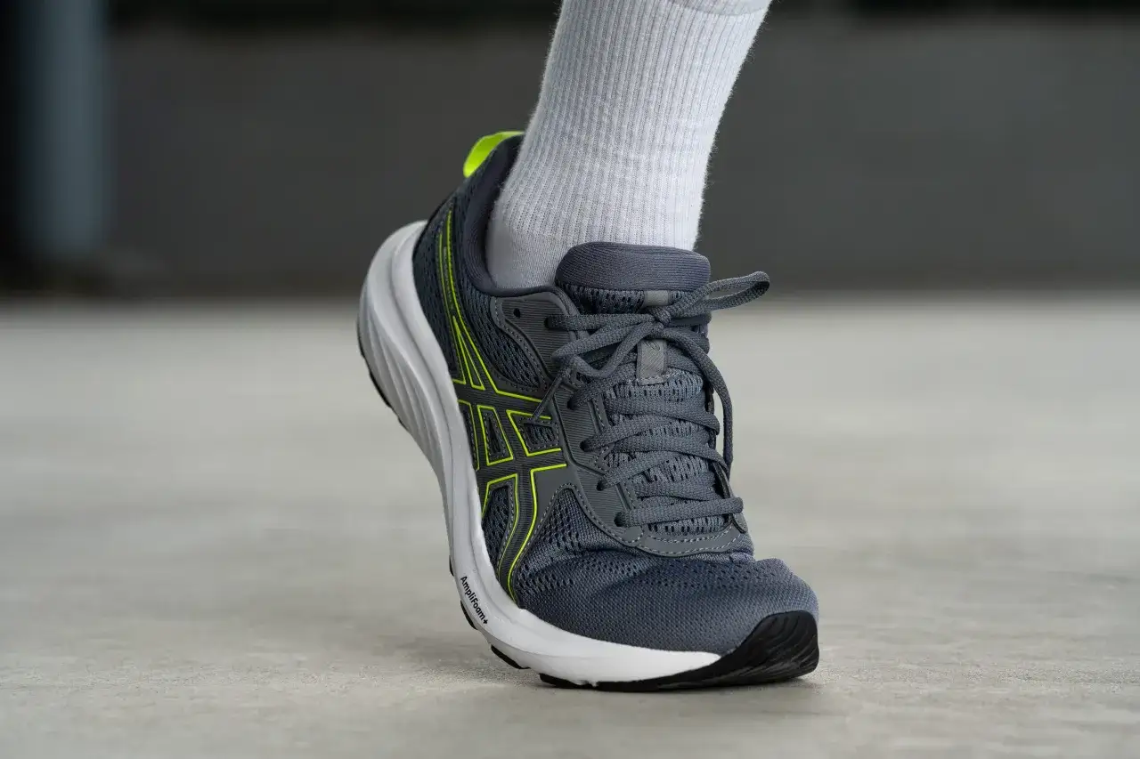 Grauer Laufschuh Asics Gel Contend 9 mit neongelben Akzenten und weißer Sohle, bereit für den nächsten Lauf.