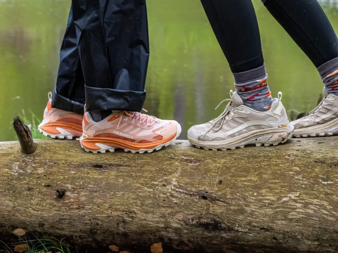 Zwei Personen stehen auf einem Baumstamm. Ihre Füße tragen Merrell Wanderschuhe, die für einen Test bereit sind.