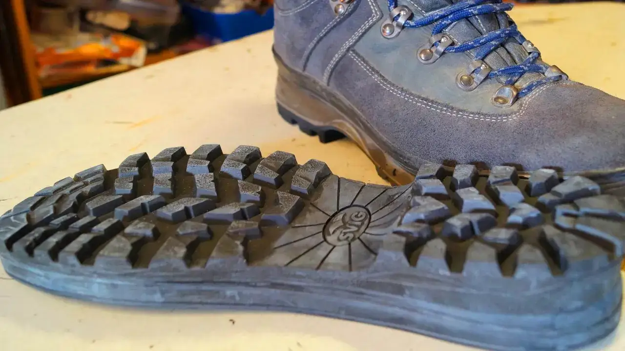 Ein Wanderschuh liegt neben seiner abgenommenen, grobstolligen Sohle. Zeit, die Schuhe besohlen lassen, damit sie wieder guten Halt bieten.