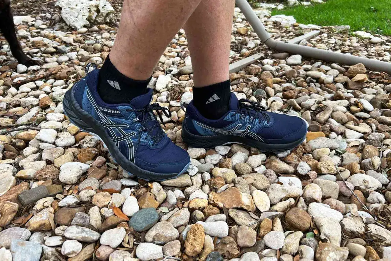 Blaue Asics Schuhe auf Steinen, ideal f&uuml;r L&auml;ufer mit Plantarfasziitis, die Komfort und Halt suchen.
