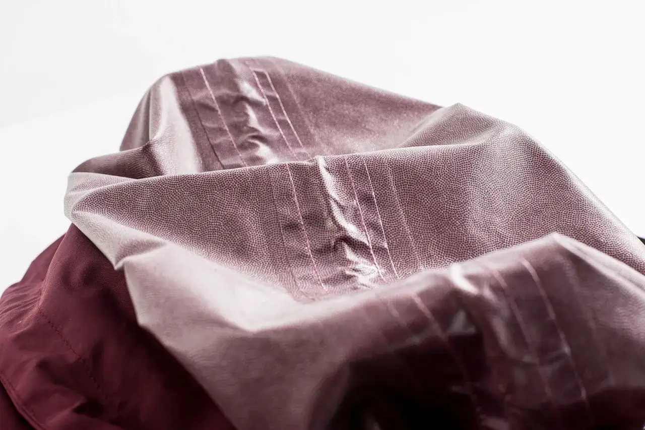 Detailaufnahme einer Kapuze, die zeigt, wie man eine Regenjacke reparieren kann. Die Nähte sind deutlich sichtbar.
