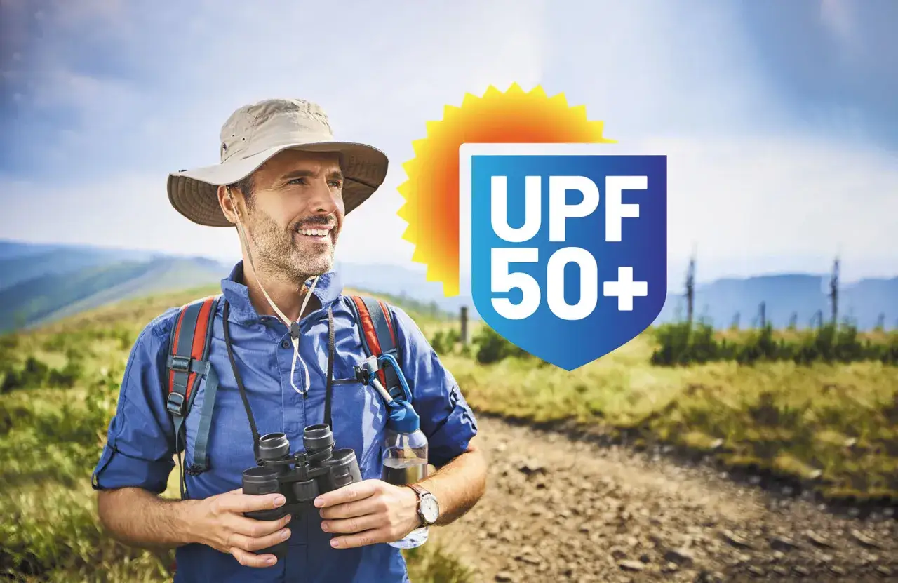 Wanderer mit Fernglas und Hut, geschützt durch UPF 50+ Bedeutung für maximale Sonnensicherheit.