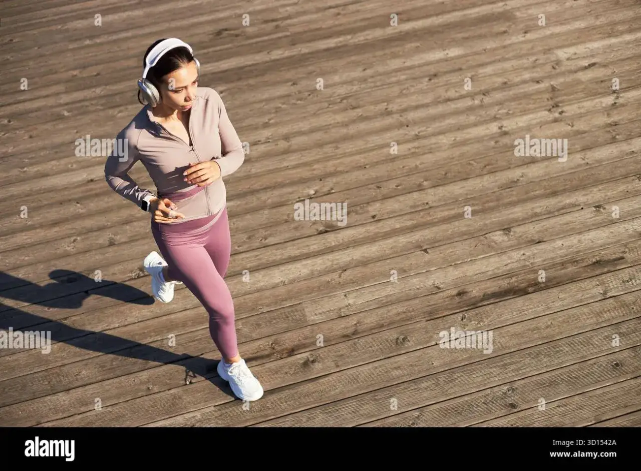 Junge Frau mit Kopfh&ouml;rern joggt auf Holzplanken, die perfekte Musik zum Joggen im Ohr.